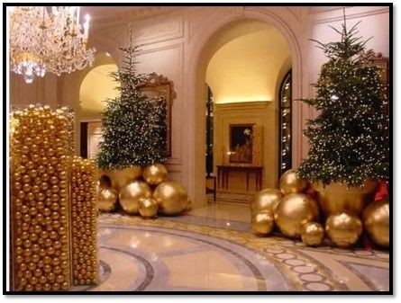 Luxurious hotel lobby decorated with Christmas trees and large golden ornaments.